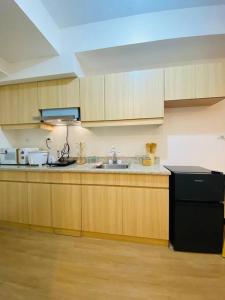 eine Küche mit Holzschränken und einem schwarzen Kühlschrank in der Unterkunft Modern Living by The Celandine DMCI in Balintawak in Manila