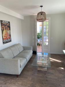 a living room with a couch and a glass table at Hôtel Chez Léonie - Chez Mamie Canne in Eugénie-les-Bains