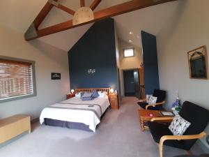 a bedroom with a bed and two chairs at Taranaki Country Lodge in New Plymouth