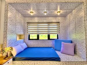 北竿鄉的住宿－花漾 森山舍，一间卧室设有蓝色的床和窗户。
