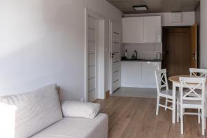 a living room with a couch and a table and a kitchen at Apartamenty Przystanek Morska in Gdynia