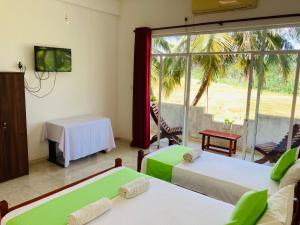 Habitación con 2 camas, TV y mesa. en Sakalya Lake View, en Tissamaharama