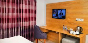 a room with a desk and a television on a wall at Hotel Afford Inn in Dhaka