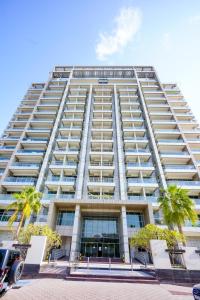 a tall white building with palm trees in front of it at Alashrafia Saray 2BR apartment in Sport City in Dubai
