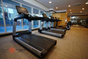 a gym with three tread machines in a room at Alashrafia Saray 2BR apartment in Sport City in Dubai