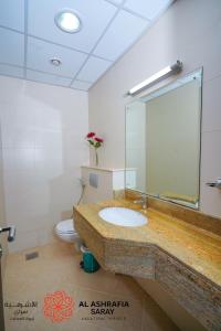 a bathroom with a sink and a toilet and a mirror at Alashrafia Saray 2BR apartment in Sport City in Dubai