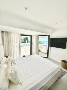 a bedroom with a large white bed with a large window at Studio H GrandBay Sea-View in Grand-Baie