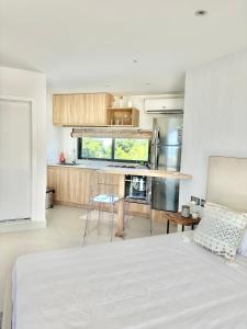 a bedroom with a white bed and a kitchen at Studio H GrandBay Sea-View in Grand-Baie