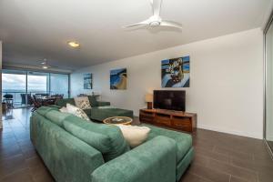 a living room with a green couch and a television at 1 Bright Point Apartment 5404 in Nelly Bay