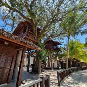 a building with a tree next to a fence at Malibest Resort in Pantai Cenang