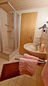 a bathroom with a sink and a shower with towels at Gästehaus Fellner in Aschau im Chiemgau