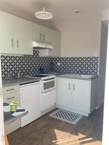 a kitchen with white cabinets and black and white tiles at Hôtel Chez Léonie - Chez Mamie Canne in Eugénie-les-Bains