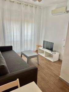 - un salon avec un canapé et une télévision dans l'établissement Apartamentos Centro Benicasim, à Benicàssim