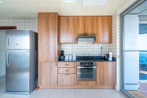 a kitchen with wooden cabinets and a stainless steel refrigerator at Veer Apartments - 82nd Floor Princess Tower - Palm View in Dubai