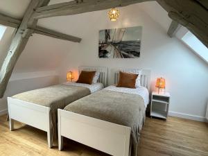 Cette chambre mansardée comprend 2 lits et 2 lampes. dans l'établissement Bella YourHostHelper, à Ouistreham