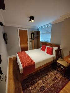 a bedroom with a large bed with red pillows at Aspen Hotel in London
