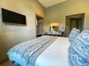 a bedroom with a bed with a tv on the wall at The Grand at Grasmere in Grasmere