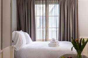 a white bed with a stuffed animal on it in front of a window at Amsterdam Canal Suites in Amsterdam