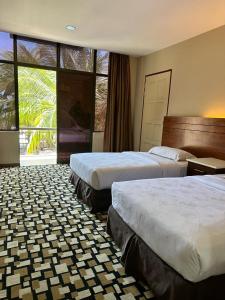 a hotel room with two beds and a large window at Malibest Resort in Pantai Cenang