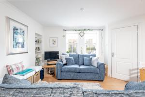 a living room with a blue couch and a tv at Stoney Creek Cottage - Cosy Cottage in the heart of Crail in Crail