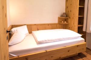 a bedroom with a wooden bed with white sheets at Natur & Spa Resort "Der Alpbacherhof" Superior in Alpbach