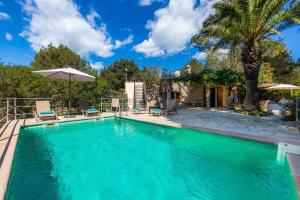 ein Swimmingpool mit Stühlen und einem Sonnenschirm in der Unterkunft Can Company in Campanet