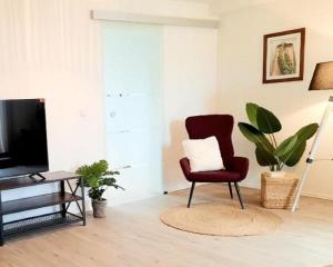 uma sala de estar com uma cadeira vermelha e uma televisão em Parkside Appartement em Grafenau