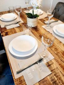 una mesa de madera con platos blancos y copas de vino en Parkside Appartement en Grafenau