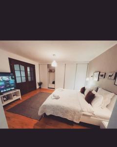 a bedroom with a large white bed and a television at Sedra House in Sighişoara