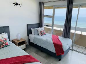 a bedroom with two beds and a view of the ocean at Serene Seascape Apartments in Amanzimtoti