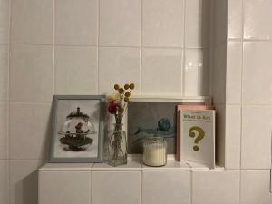 a shelf with two pictures and a book and flowers at 1 room apartment in Friedrichshain in Berlin