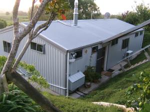 a small white house with a porch and a tree at Memory Lane Country Cottage in Cambridge