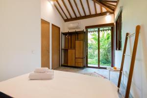 sypialnia z białym łóżkiem i przesuwnymi szklanymi drzwiami w obiekcie Singgah di Ubud 2 w mieście Ubud