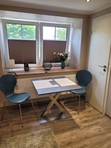 a table and chairs in a room with two windows at Burghaus 2 in Greetsiel