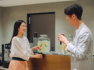 un homme et une femme debout devant un comptoir dans l'établissement HOTEL THE LEBEN OSAKA, à Osaka