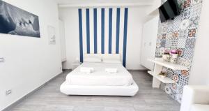 a white room with two beds and a striped wall at Eremo sul Mare in Marina di Fuscaldo