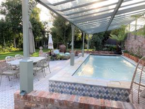 Lyndhurst - Victorian villa with heated pool في Roby: مسبح تحت البرغولية مع طاولة وكراسي