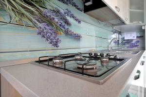 a stove top in a kitchen with purple flowers on the wall at Apartment Opatija Lavanda in Opatija
