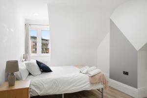 3BR Duplex Penthouse Harrow centre في هارو: غرفة نوم بيضاء بها سرير ونافذة