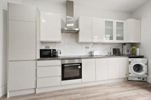 a white kitchen with white cabinets and a microwave at 3BR Duplex Penthouse Harrow centre in Harrow +14 photos