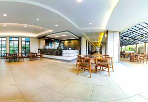 a dining room with tables and chairs in a building at Mangrove Prestige Hotel in Na Jomtien
