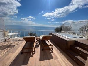 una terraza con bañera de hidromasaje y 2 sillas en SeaJewelsDeluxurySuite, en Amalfi