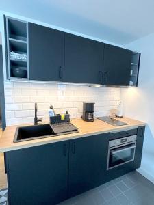 a kitchen with a sink and a counter top at Alpenglühen Smart Hotel in Olching