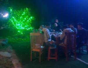 un grupo de personas sentadas en una mesa en un acuario por la noche en Trang an green river homestay en Ninh Binh