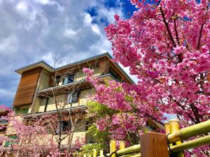 a tree with pink flowers in front of a building at Kadensho, Arashiyama Onsen, Kyoto - Kyoritsu Resort in Kyoto