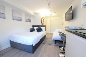 a bedroom with a bed and a desk with a television at London Studios Very Close to Central Line Underground Shepherds Bush and Westfield Newly Refurbished in London