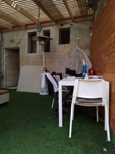 eine Terrasse mit einem Tisch und Stühlen auf grünem Gras in der Unterkunft צימר מפואר שבתות וחגים in Bet Schemesch