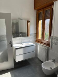 a white bathroom with a sink and a mirror at Casa del Faggio Rosso in Bellagio