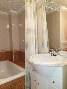 bagno con lavandino, vasca e specchio di Apartamento Ángel en Palma a Benidorm
