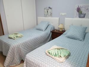 2 letti in una camera con lenzuola bianche e blu di Apartamento Ángel en Palma a Benidorm